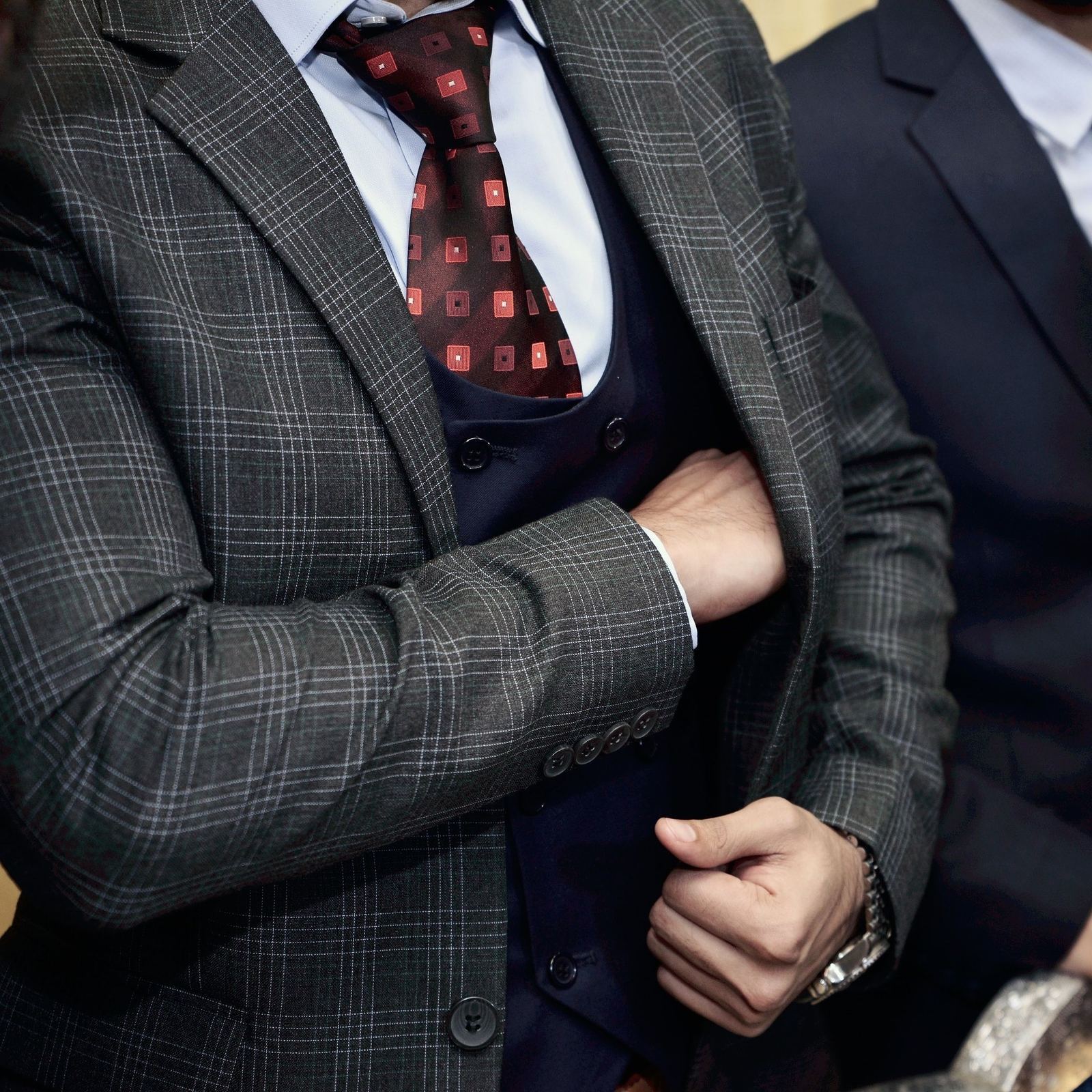 Homem com terno elegante ajustando a gravata, em close detalhado da alfaiataria de luxo