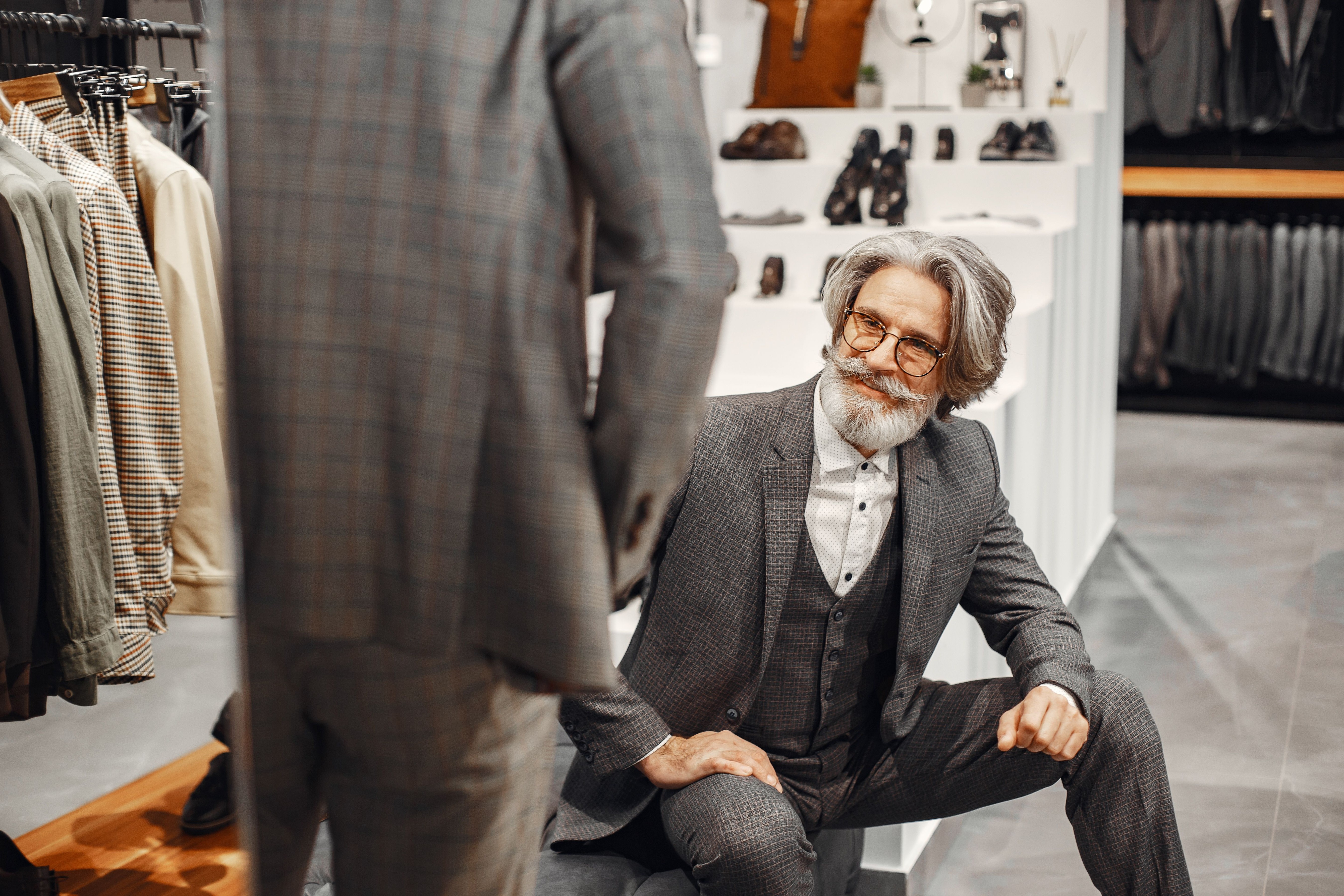 Homem elegante examinando terno xadrez em boutique de moda masculina
